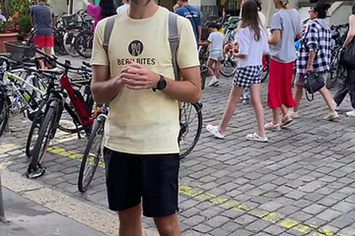 BernBites Guide auf Berns Altstadt-Pflaster, im Hintergrund Passanten